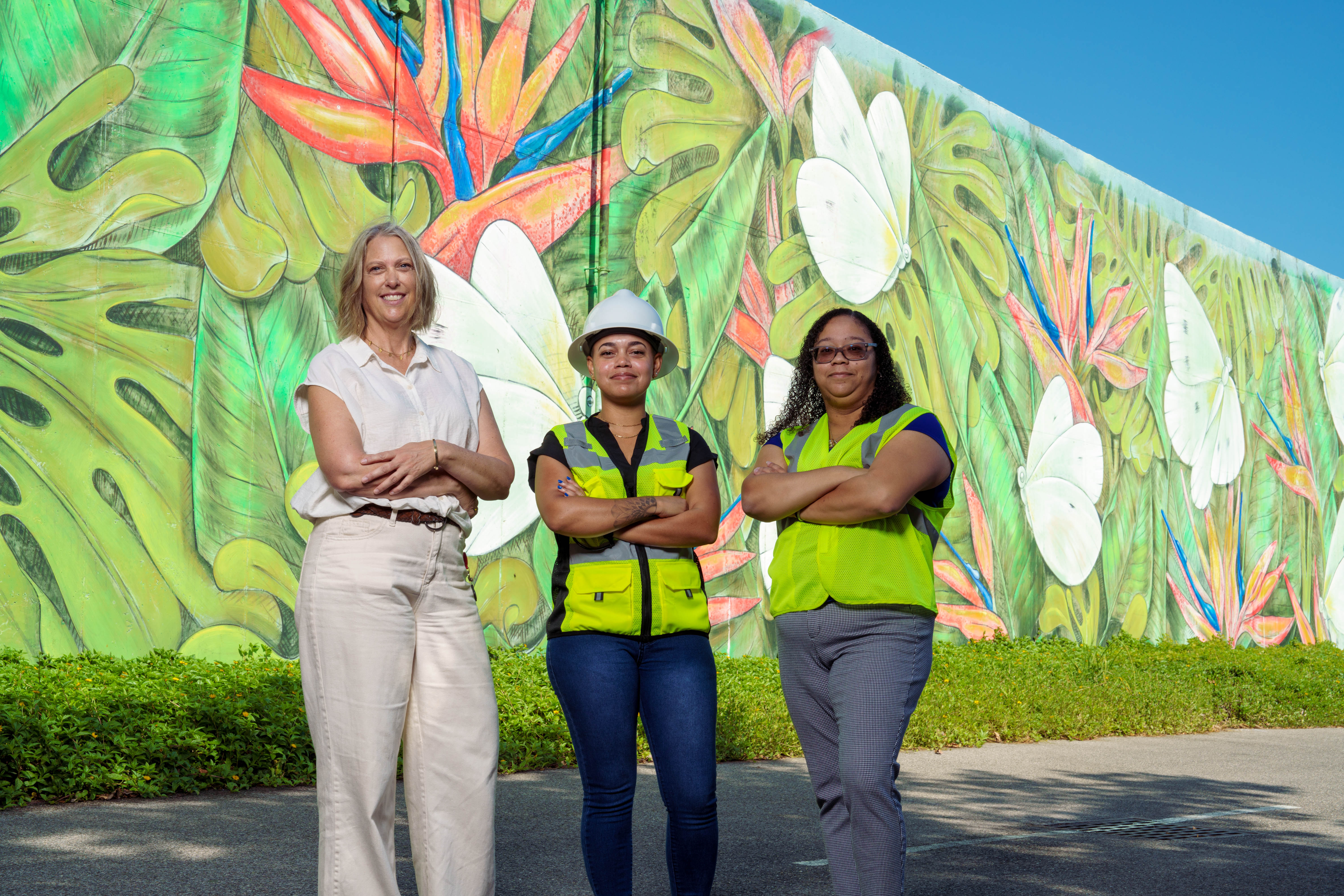 Women posing in front of mural